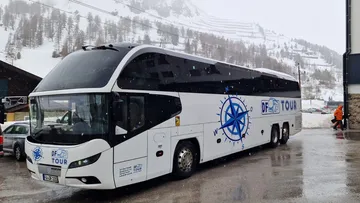 Tour bus parked in snowy mountain area.