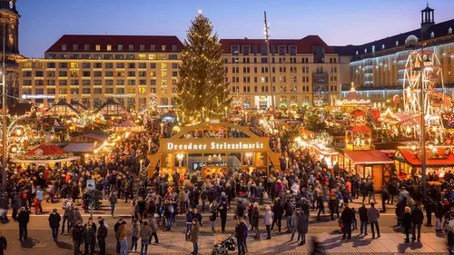 Weihnachtsmarkt mit Baum bei Dämmerung.