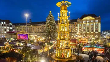 Illuminated Christmas market with tall tower.