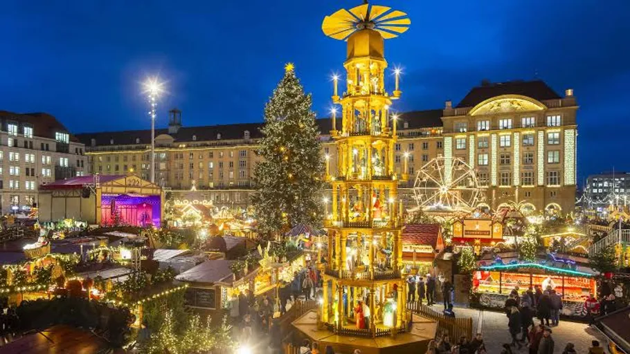 Beleuchteter Weihnachtsmarkt mit hohem Turm.