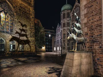 Bronzeskulptur von Tieren in einer ruhigen, nächtlichen Stadtlandschaft.