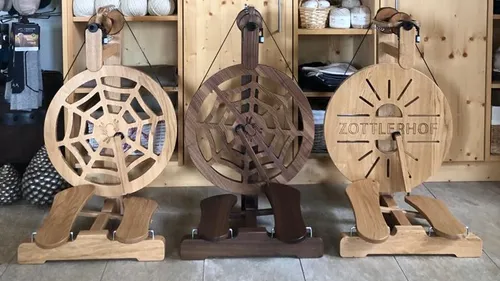 Three decorative wooden spinning wheels displayed indoors.