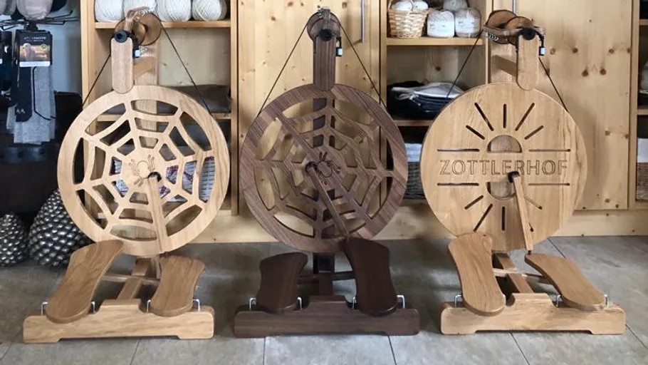 Three decorative wooden spinning wheels displayed indoors.