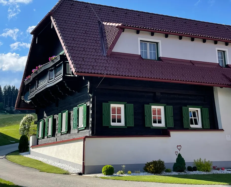 Traditional house with green shutters, countryside setting.