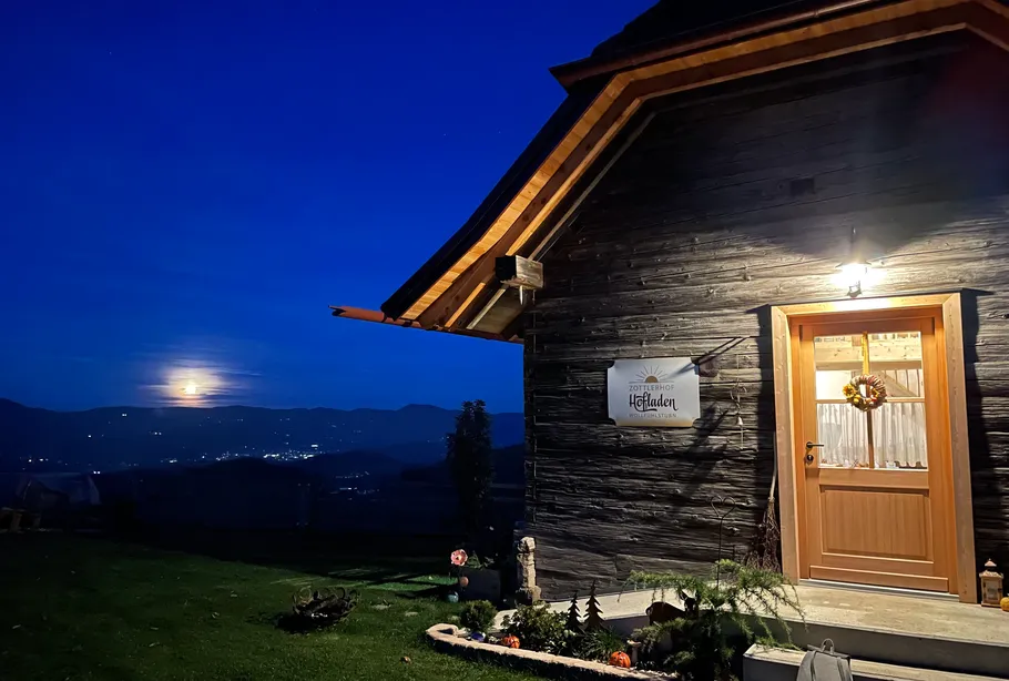Cottage with sign, garden under night sky.