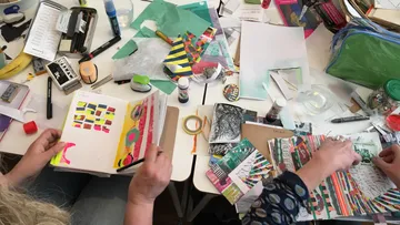 Zwei Personen basteln mit buntem Papier.