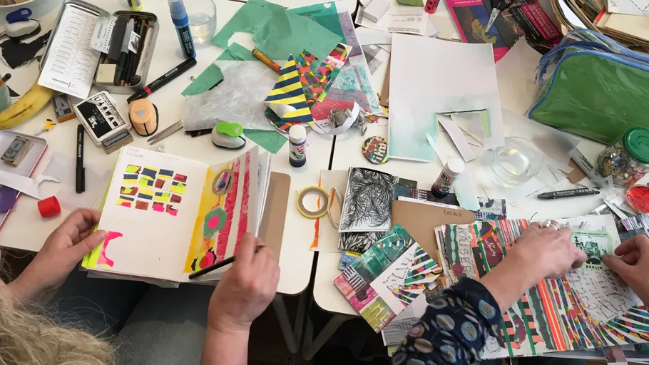 Zwei Personen basteln mit buntem Papier.