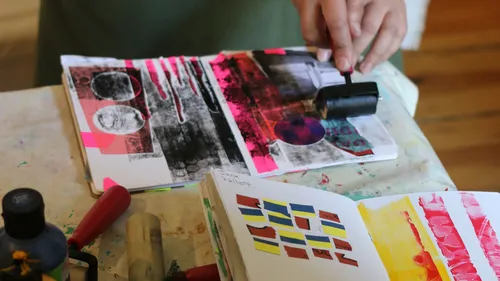 Person creating art in sketchbook with roller.