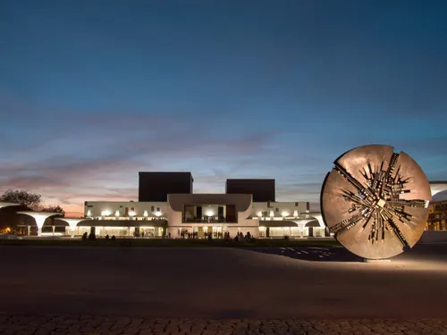 Modern architecture glows while a sculpture is standing.