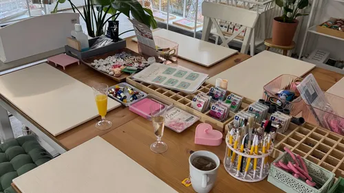 Craft table setup with tools and beverages.