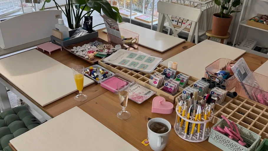 Craft table setup with tools and beverages.