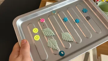 Hand hält Tablett mit bunten Tonformen.
