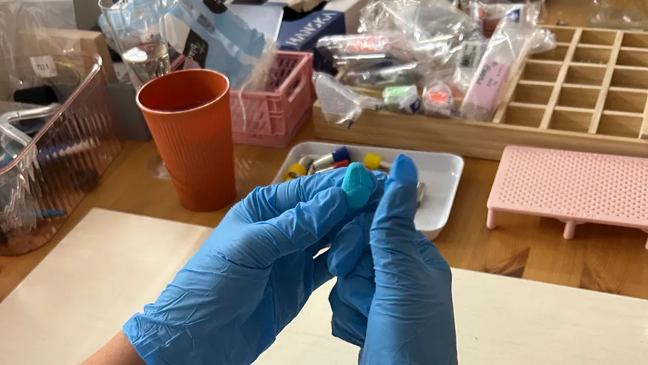 Hands wearing gloves holding a blue object.