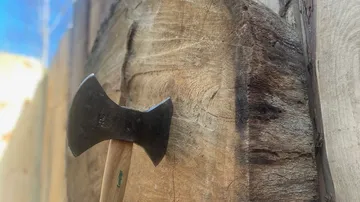 Axt steckt in Holzscheibe im Freien.