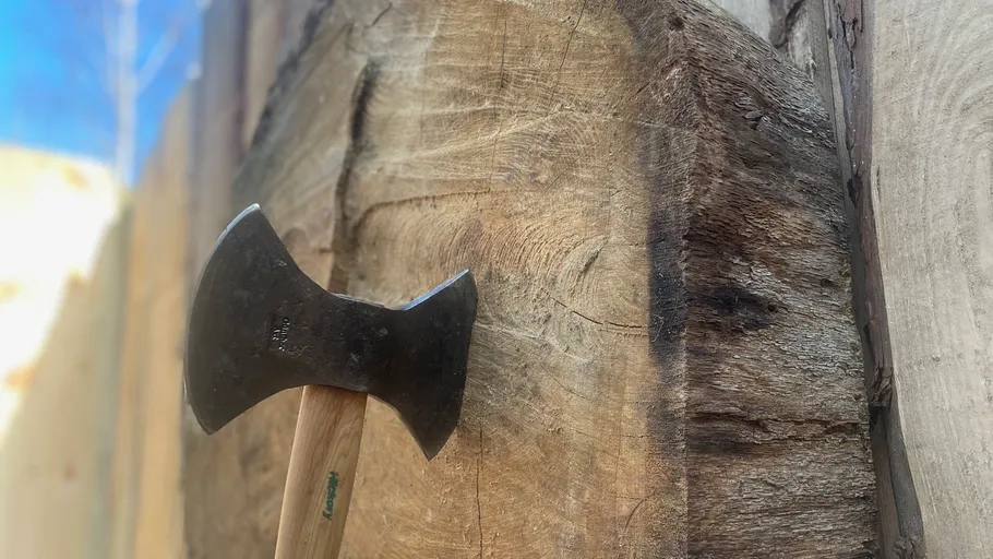 Axe stuck in wooden target outdoors.