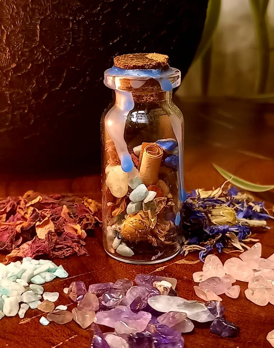 Glasflasche mit Kristallen und Blumen gefüllt.