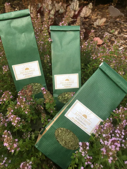 Green herb packages in garden with flowers.