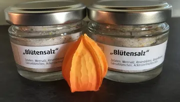Zwei Gläser mit 'Blütensalz' und orangefarbenem Blütenblatt.