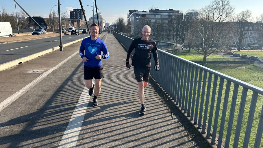 Two men jogging on a bridge.
