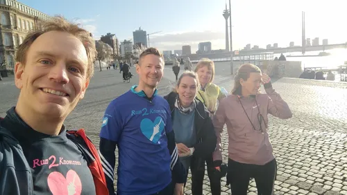 Group of runners posing on cobblestone street.