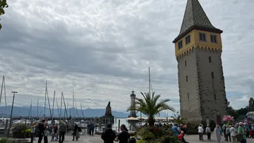 Tower near harbor with people and boats.