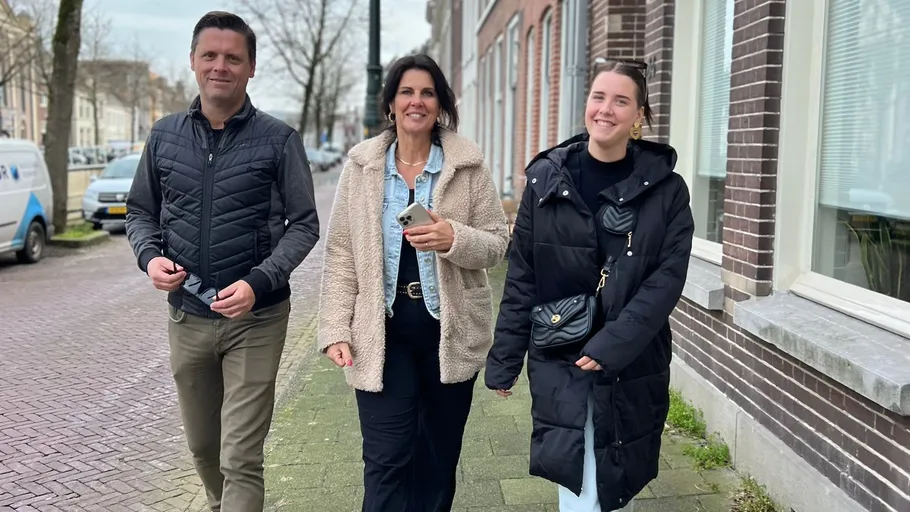 Three people walking on a city sidewalk.