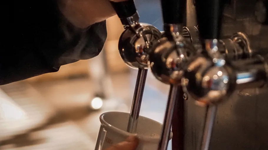 Person pouring beverage from tap into cup.
