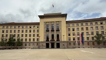 Großes Regierungsgebäude mit Flaggen und Hof.
