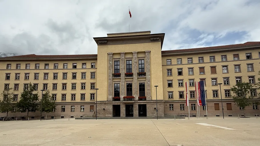 Large governmental building with flags and courtyard.