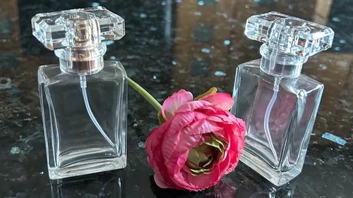 Zwei Parfümflaschen mit einer pinken Blume.