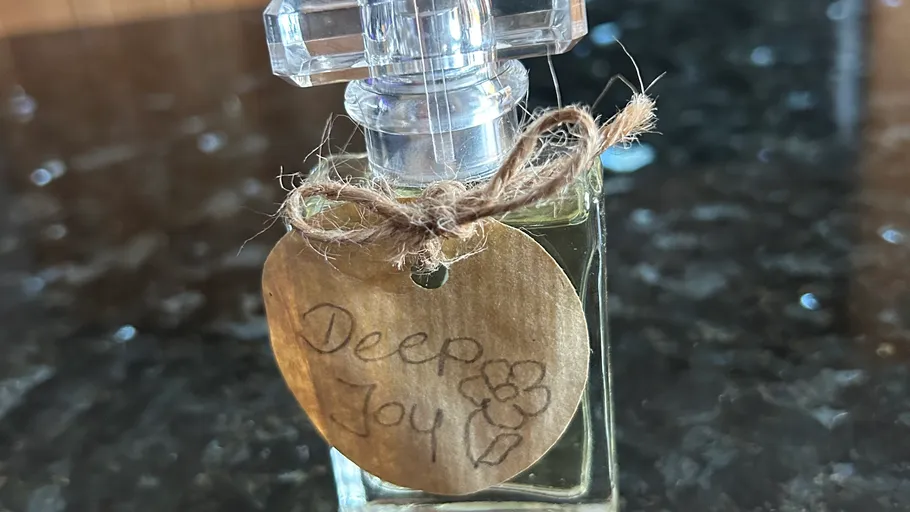 Parfümflasche mit handgeschriebenem Etikett, rustikale Oberfläche.