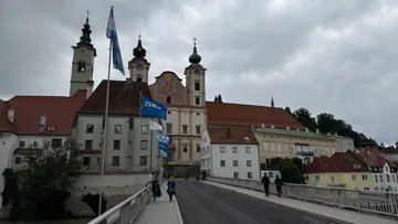 Personen gehen auf Brücke Richtung Altbauten.
