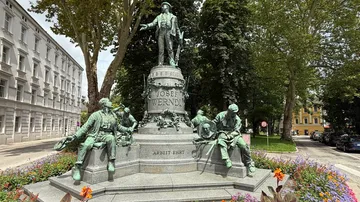 Statue surrounded by flowers in urban park.