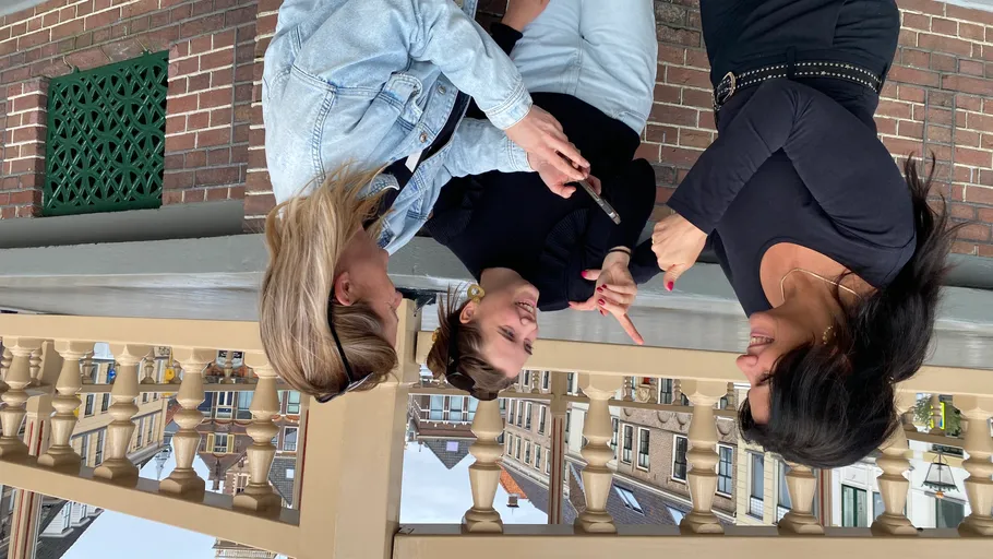 Drei Frauen reden, Holzgeländer, städtischer Hintergrund.