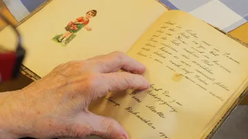 Hand blättert in einem alten Buch.