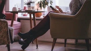 Person sitting in a chair using smartphone indoors.