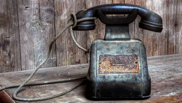 Altes Wählscheibentelefon auf Holztisch.