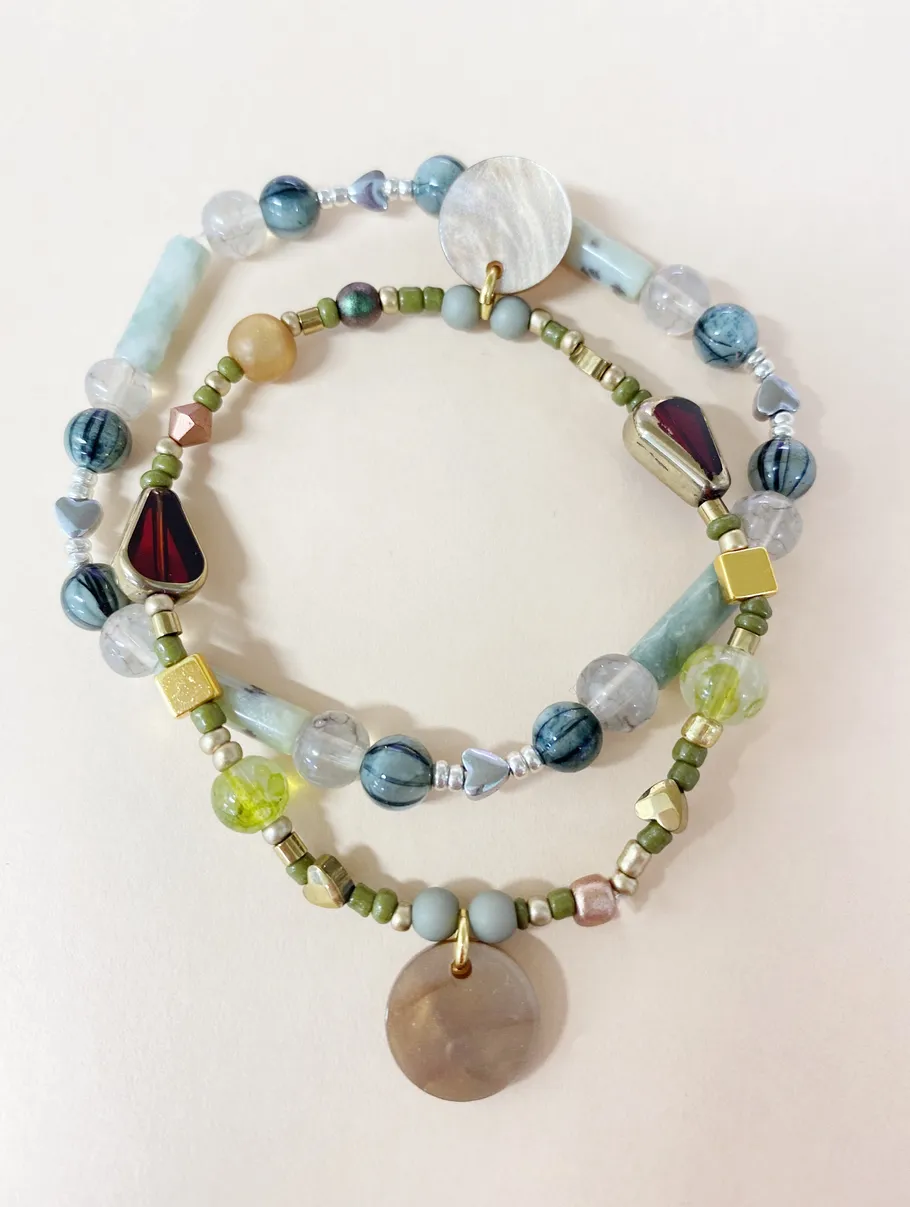 Beaded bracelets with round stone pendants.