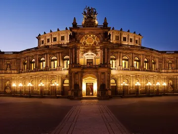Historic building glows against a blue sky at night.