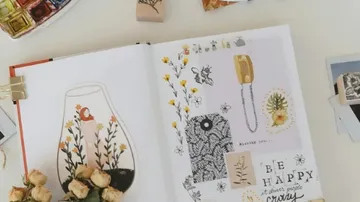 Offenes Scrapbook mit Blumendekorationen, Stempeln und Text.