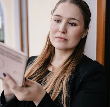 Frau liest eine Karte am Fenster.