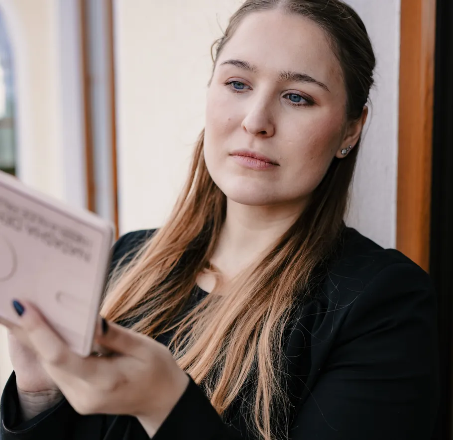 Woman reading a card near a window.