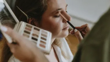 Woman having eyeshadow applied, relaxed atmosphere.