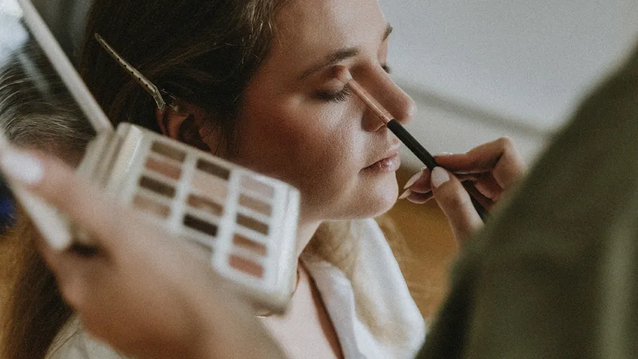 Woman having eyeshadow applied, relaxed atmosphere.