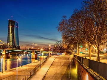 Hochhaus leuchtet, während die Brücke über den Fluss führt.