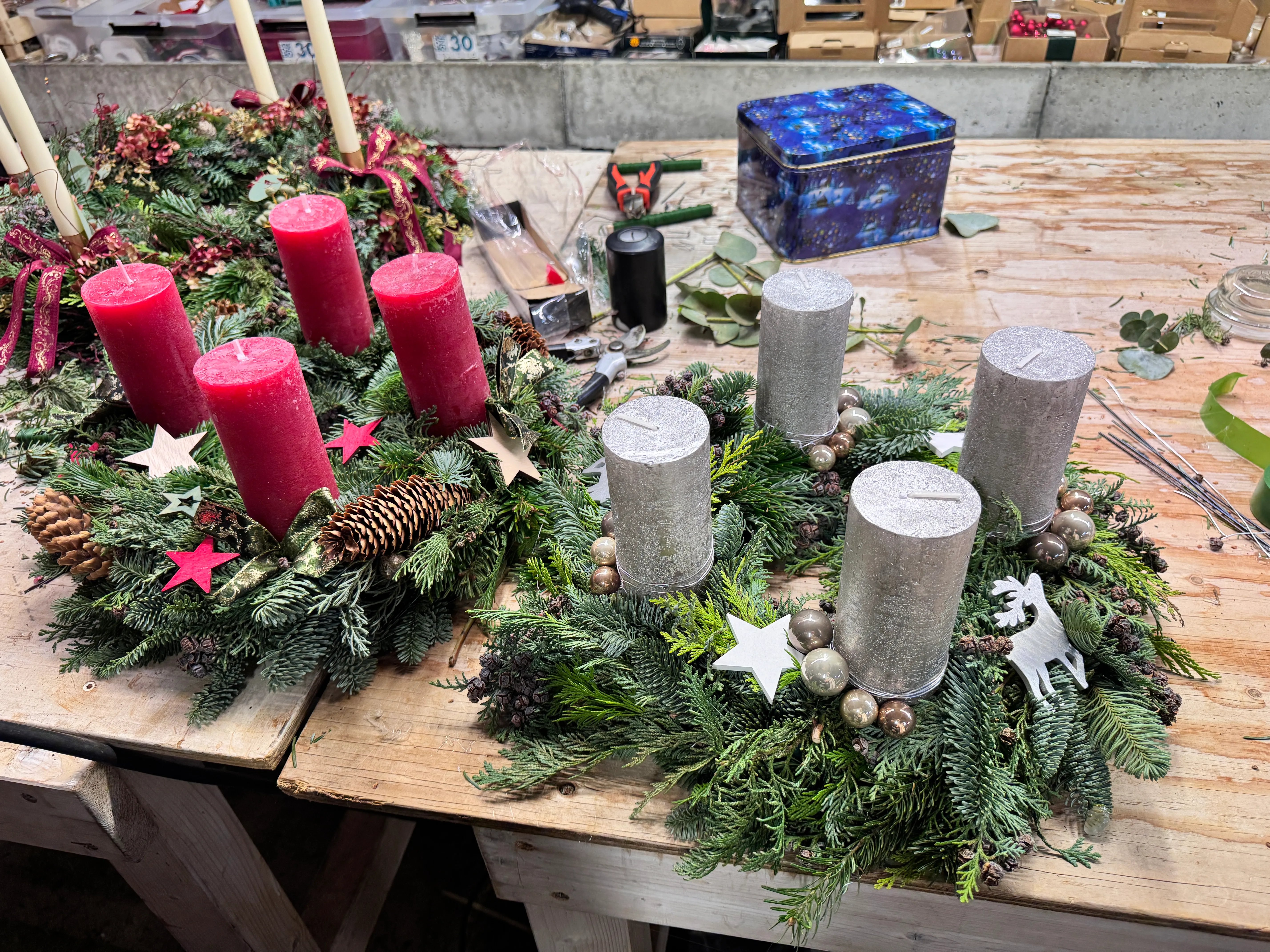 Adventskränze mit Kerzen auf Holztisch.