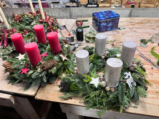 Adventskränze mit Kerzen auf Holztisch.