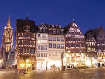 Historische Gebäude stehen leuchtend in der Nacht, Kirchenkuppel sichtbar.