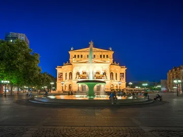 Fountain bubbles in front of an illuminated building in the evening.