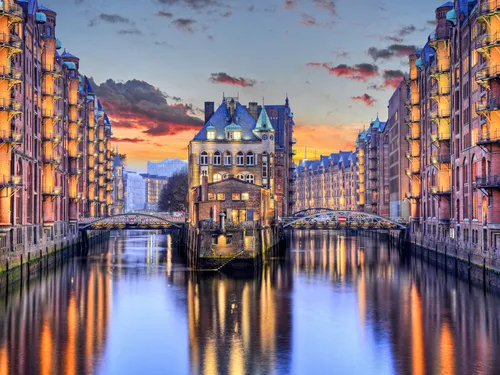 Kanal mit historischem Gebäude, zwischen beleuchteten Ziegelhäusern.
